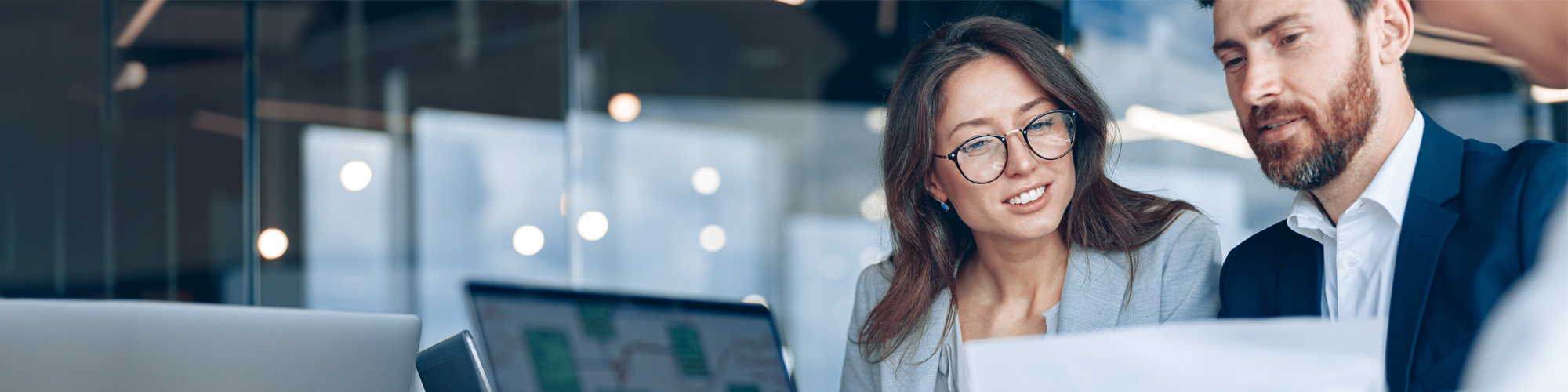 Foto: junge Frau und junger Mann vor Computer an einem Schreibtisch