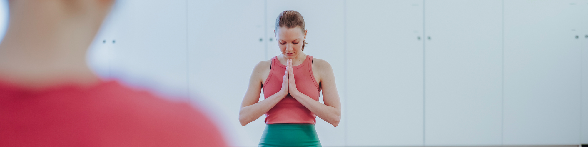 Junge Frau in Qigong-Kurs mit gefalteten Händen