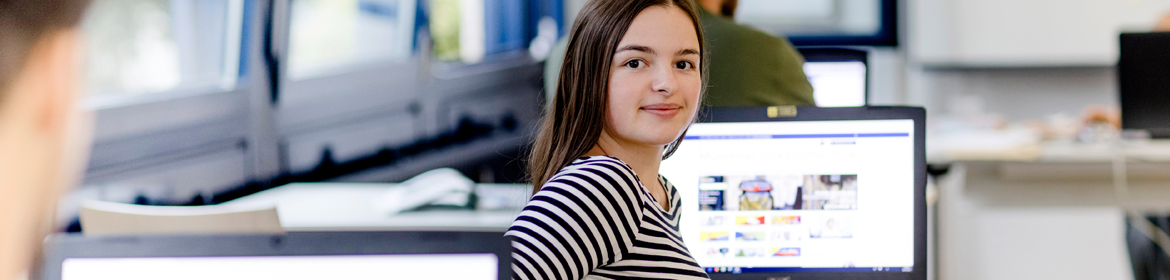 Jugendliche sitzt in einem Schulungsraum vor einem Bildschirm mit der MVHS Homepage