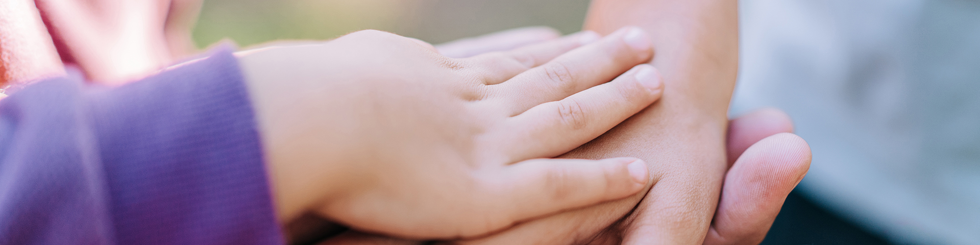 Foto: Hände übereinander, ganz oben eine kleine Kinderhand
